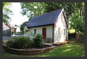 a small white house with a red door at Cute cottage for short getaway in Cross Mahon
