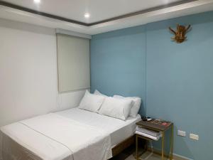 a small bed in a room with a blue wall at Hotel Boulevard 58 in Galapa