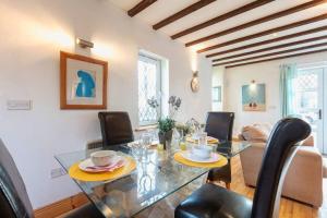 a dining room with a glass table and black chairs at Cute cottage for short getaway in Cross Mahon +10 photos
