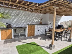 an outdoor kitchen and dining area with a wooden pergola at Casa Federico & Manuela – Piscina Climatizada in Mogán