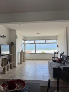 a living room with a couch and a view of the ocean at Apartamento em frente ao mar in Guarujá