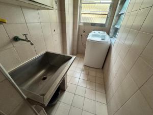 a bathroom with a sink and a washing machine at Apartamento em frente ao mar in Guarujá