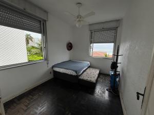 a room with a bed and two windows at Apartamento em frente ao mar in Guarujá