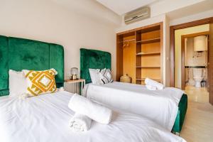two white beds with green headboards in a room at la cocon paisible de Marrakech in Marrakech +19 photos