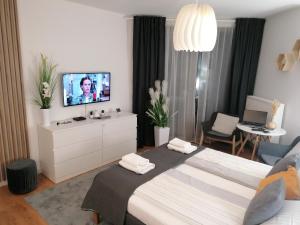 a bedroom with a large bed with a tv on it at PINEA Apartament z widokiem na morze z basenem i SPA przy plaży in Pobierowo