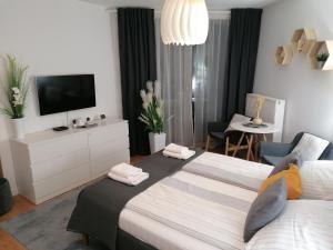 a bedroom with two beds and a tv and a living room at PINEA Apartament z widokiem na morze z basenem i SPA przy plaży in Pobierowo