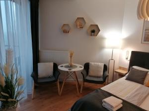 a bedroom with a bed and two chairs and a table at PINEA Apartament z widokiem na morze z basenem i SPA przy plaży in Pobierowo
