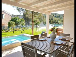 a dining table and chairs with a pool in the background at Villetta con piscina e ampio giardino in Stintino