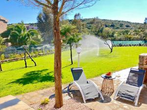 two chairs and a table in a park with a fountain at Villetta con piscina e ampio giardino in Stintino
