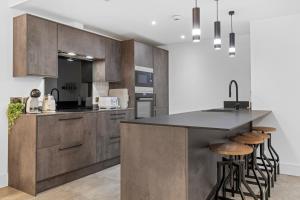 eine Küche mit Holzschränken und eine Insel mit Barhockern in der Unterkunft Luxury 2-Bed Apartment with Parking & Terrace in Nottingham