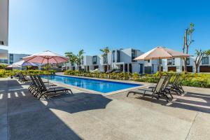 a swimming pool with chairs and umbrellas in front of a building at Ebano Residential in Las Juntas