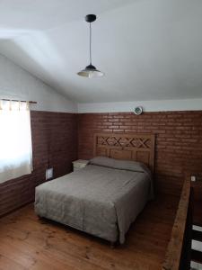 a bedroom with a bed and a brick wall at Sonidos del Rio Aparts in Santa Rosa de Calamuchita