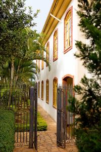 a gate in front of a white house with yellow windows at Villa Douro Hotel in Tiradentes