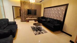 a living room with couches and a table and a tv at Hotel Oasis in Islamabad