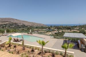 a swimming pool with palm trees and a hill in the background at Villa Lefkothea in Georgioupoli