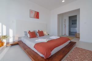 a white bedroom with a large bed with orange pillows at Villa Gold with ocean view in Ribamar