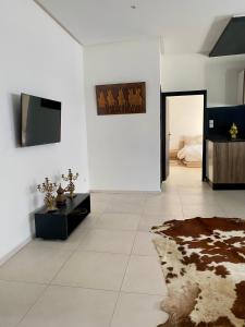 a white living room with a television and a rug at L'IMPERIAL SVD Studio a votre disposition in Fès