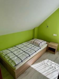 een groene slaapkamer met een bed en een tafel bij Domki Letniskowe Konik 3 in Radków