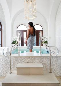 a woman standing in front of a mirror in a tub at The Oyster Box in Durban