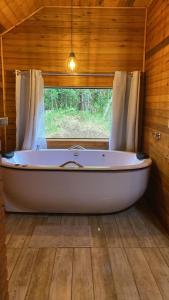 a bath tub in a room with a window at Chalés Canto da Serra in Monte Verde