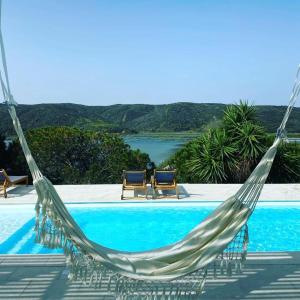a hammock in front of a pool with two chairs at Herdade d' Amoreira Lavanda Villa in Aljezur