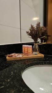 a bathroom counter with a sink and a shelf with products at Caraguá Flat in Caraguatatuba +10 photos