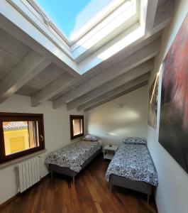 two beds in a room with a skylight at Garda Girasole trilocale a due passi dal lago con posto auto privato in Desenzano del Garda