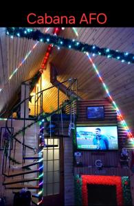 una stanza con una scala, una televisione e luci di Natale di Cabana AFO A Frame a Brăteasca