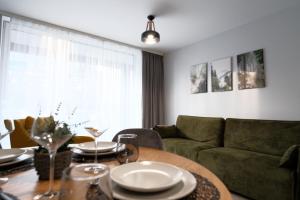a living room with a table and a green couch at Laguna Beskidów Resort - Apartament Simple Comfort in Zarzecze +22 photos