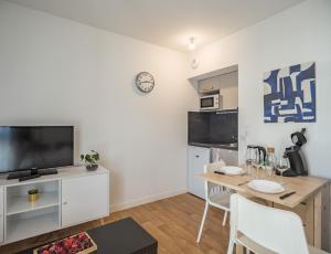 a living room with a dining room table and a kitchen at Le Cocon de l'Artiste - moderne, artistique et cosy ! in Troyes