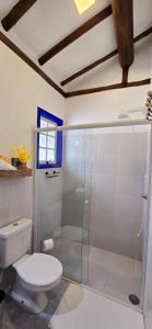a bathroom with a toilet and a glass shower at Suíte Kuta - Buddha House in Ilhabela