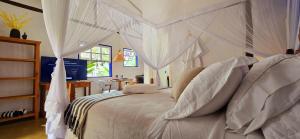 a bedroom with a white bed with white drapes at Suíte Kuta - Buddha House in Ilhabela