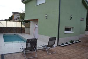 two chairs sitting next to a building with a pool at El huerto de la Dominga in Segovia