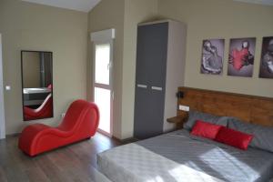 a bedroom with a bed and a red chair at El huerto de la Dominga in Segovia +20 photos