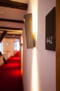 a hallway with red carpet and a wall with lights at Hotel Schloss Waldeck in Waldeck