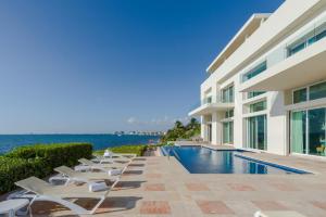 a villa with a swimming pool next to the ocean at Villa Punta Sam - Beachfront Luxury Villa in Cancún