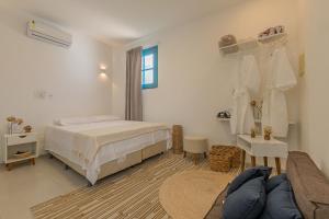 ein weißes Schlafzimmer mit einem Bett und einer Couch in der Unterkunft Suíte Organic Cumbuco na Melhor Localização by CDH in Cumbuco