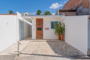 ein weißes Haus mit einer Holztür in der Unterkunft Suíte Organic Cumbuco na Melhor Localização by CDH in Cumbuco