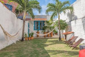 ein Haus mit Palmen und einer Hängematte im Hof in der Unterkunft Suíte Organic Cumbuco na Melhor Localização by CDH in Cumbuco