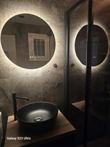 a bathroom with a sink and a round mirror at LuxuryGuesthouse AXD in Alexandroupoli