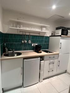 a kitchen with white cabinets and a sink and green tiles at Studio au cœur de Cannes in Cannes +3 photos