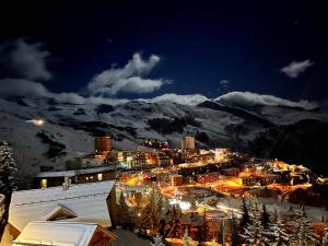 a view of a city at night with a mountain at Terrasse, vue imprenable et accès direct pleine nature, votre refuge idéal in Orcières