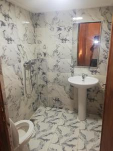 ein Badezimmer mit Waschbecken, Toilette und Spiegel in der Unterkunft Dâr Mâbâ in Tazenakht