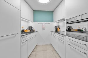 a white kitchen with white cabinets and appliances at Gemütliche 2.5 Zimmer Wohnung mit privater Sauna in Seewis im Prättigau