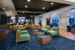a lobby with chairs and tables and a restaurant at Courtyard Tallahassee North/I-10 Capital Circle in Tallahassee