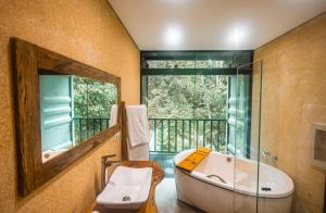 a bathroom with a tub and a large mirror at I am Boutique Hotel Campos do Jordão by Unna in Campos do Jordão