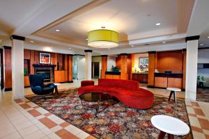 eine Lobby mit einem roten Sofa und einem Tisch und Stühlen in der Unterkunft Marriott Fairfield Sudbury in Sudbury