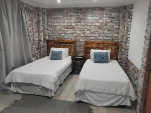 2 letti in una camera con muro di mattoni di Corner House Cottages a Grootfontein