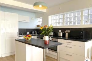 eine Küche mit weißen Schränken und einer schwarzen Arbeitsplatte in der Unterkunft Le Bord de Mer - Vue Mer - Terrasse - Parking in Le Havre + 25 Fotos