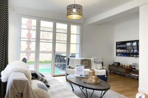 a living room with a couch and a table at The Garden House - Jardin Parking Hypercentre in Deauville